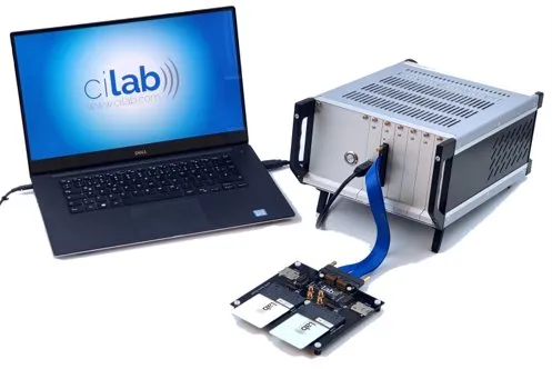 A cilab ci200 developer unit on a desk — a laptop running the cilab software, the compact tester and a demo board connected by a blue flex cable