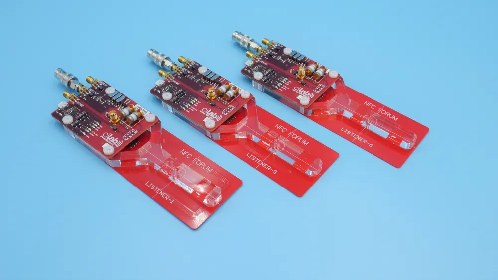 Red NFC Forum reference listener antenna (LISTENER-1) on the robot arm of a ci230 bench